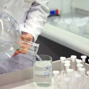 Laborantin versant un liquide chimique dans un bocal en verre